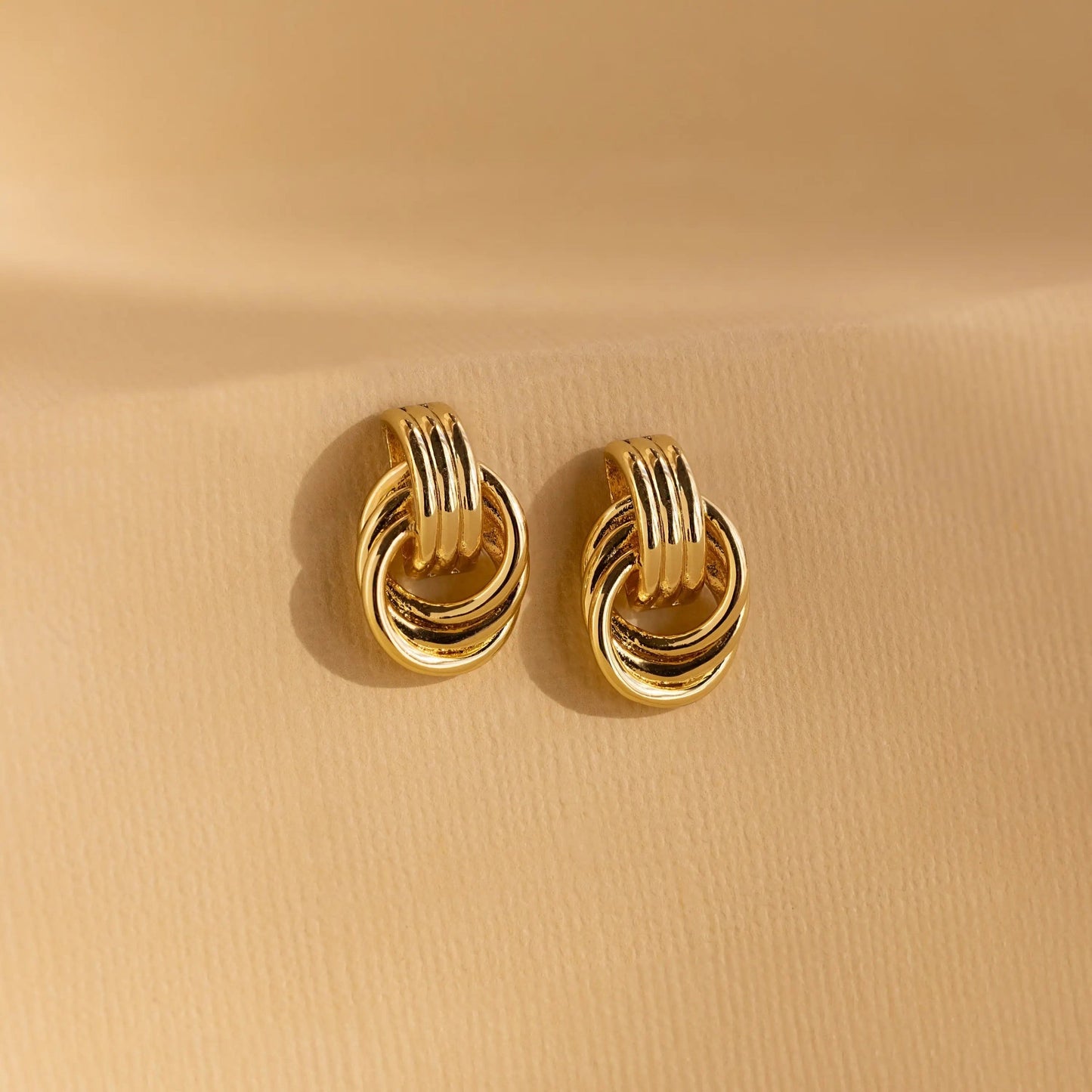 Flatlay of Clean Knot earrings styled with minimalist accessories