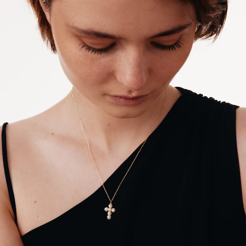 Close-up of dainty pearl cross necklace details