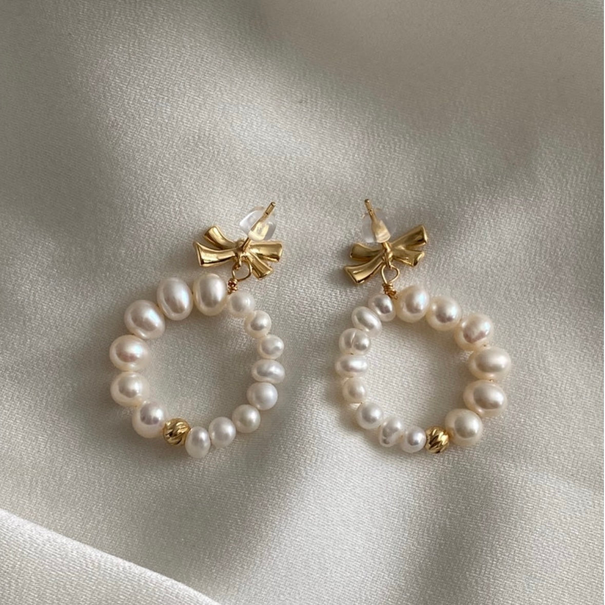 Pearl bow tie huggie earrings – front view in gold