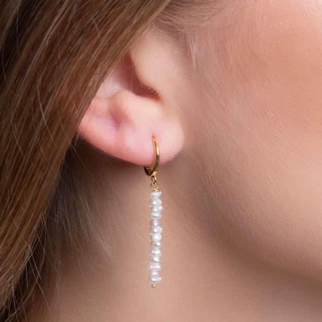 Close-up of natural pearl earrings with gold hoops