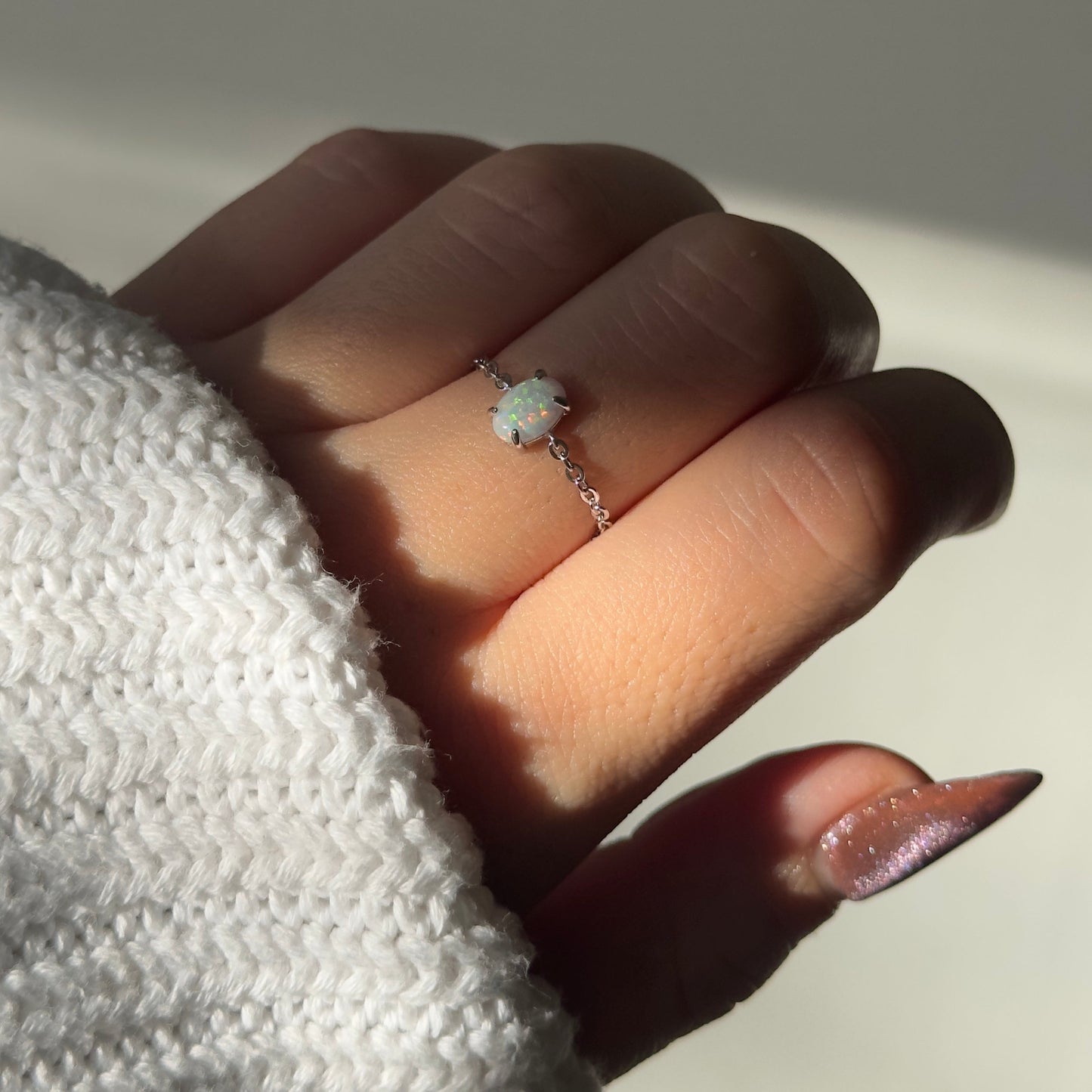 Close-up of lab-grown white opal on dainty adjustable chain ring