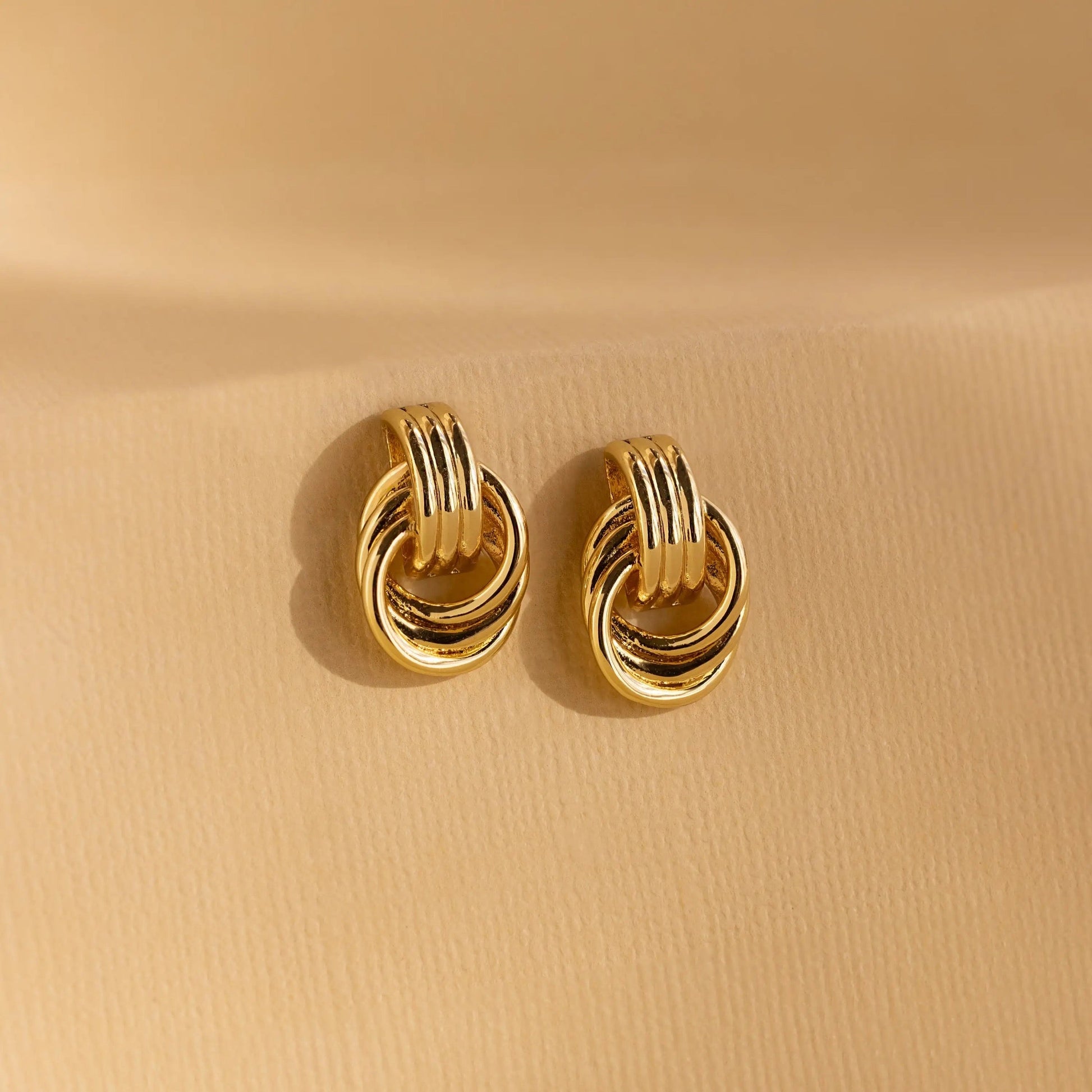 Flatlay of Clean Knot earrings styled with minimalist accessories