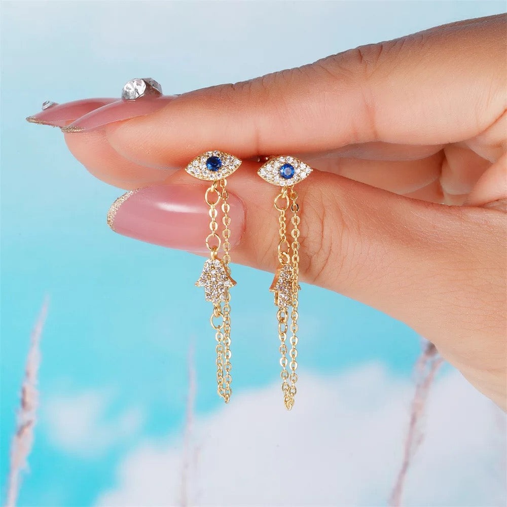 Close-up of gold evil eye earring with chain